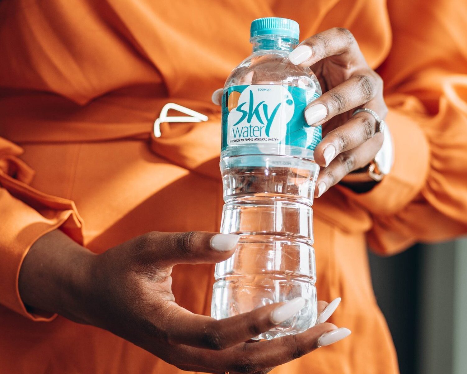 Woman holding Skywater brand water I. pep bottle.